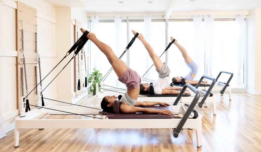 Pilates teacher giving hands-on cue to a student during Pilates teacher training certification course in Astoria, New York City.